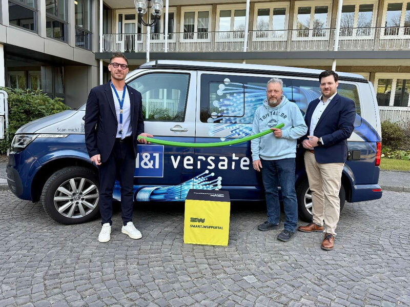 3 Männer stehen vor einem Bulli mit 1&1 Versatel Logo: Patrick Tomasikiewicz (Communal Manager), Claas Claaßen (Gigabitkoordinator der Stadt Wuppertal) und Christian Kussmann (Head of Infrastruktur Süd/West) bei der symbolischen Glasfaser-Übergabe in Wuppertal (v.l.n.r.).