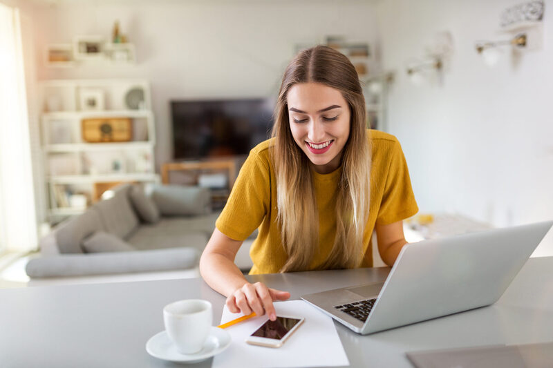 Frau arbeitet mit Laptop und Smartphone Zuhause